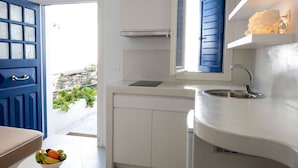 A modern kitchen with white cabinetry, a built-in stove, and a window with blue shutters. - Hyades - Downtown Suites No 3 , Mykonos Town (Mykonos, Cyclades)