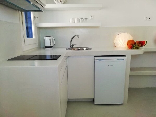 Una cocina compacta con lavavajillas integrado, tetera y fregadero.