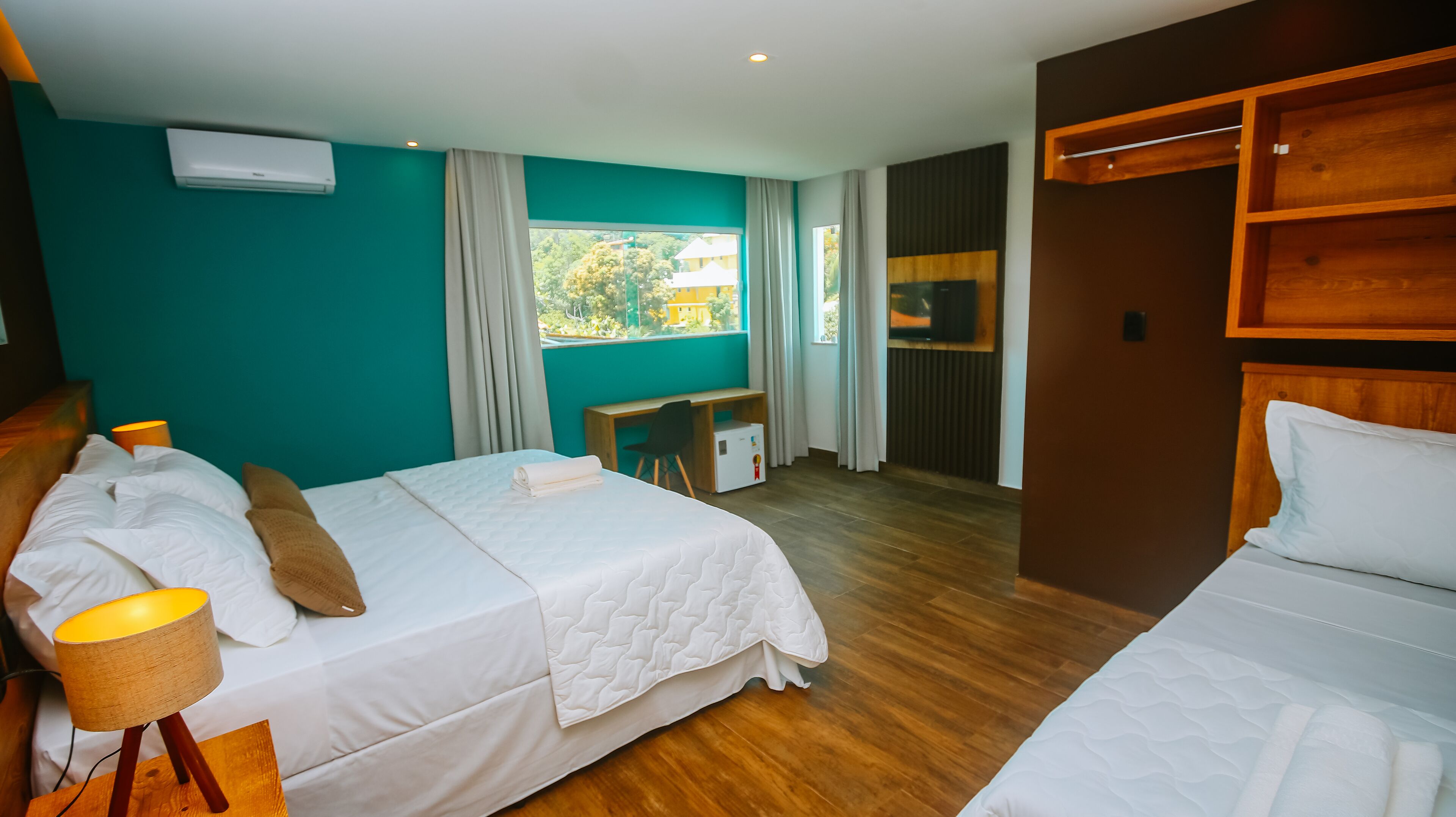 Una habitación de hotel con dos camas, un escritorio, una silla y un televisor.