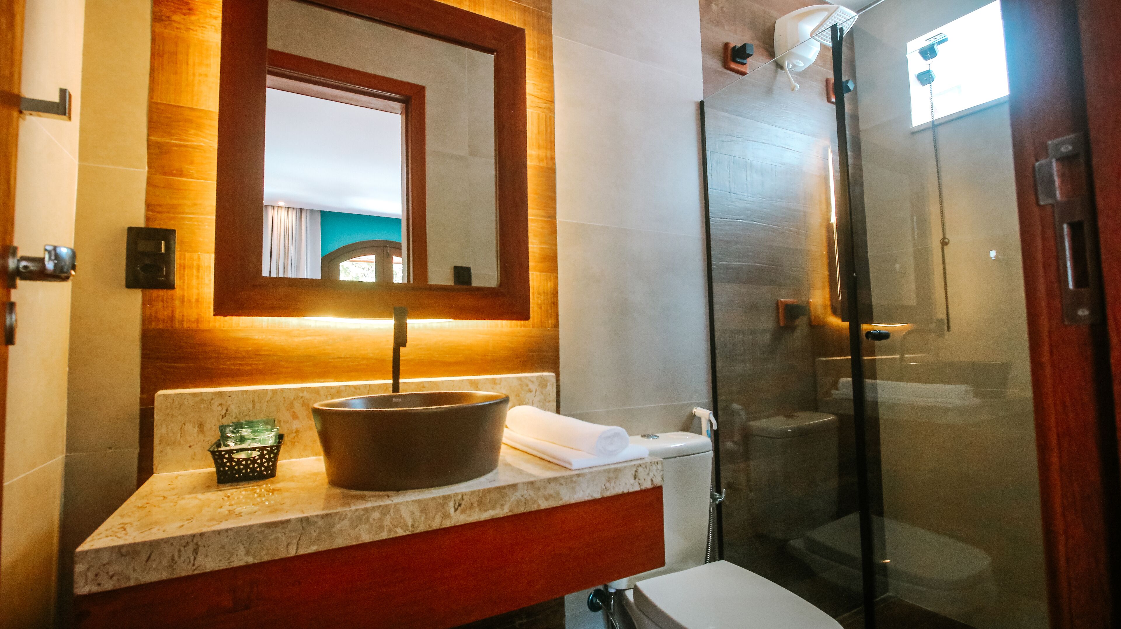 Une salle de bain dotée d’un comptoir en marbre, d’un grand lavabo, d’un miroir et d’une douche à parois de verre.