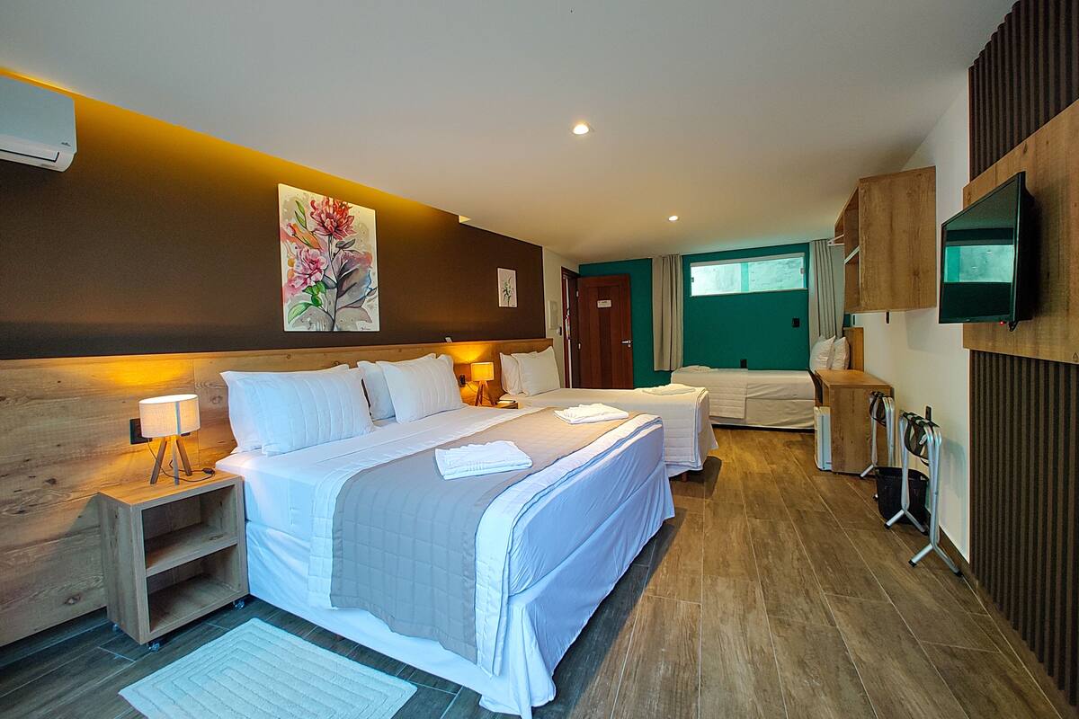 A hotel room with a large bed, bedside tables, a TV, and a window with curtains.