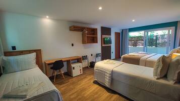 A hotel room with two beds, a desk, a small refrigerator, and a TV.