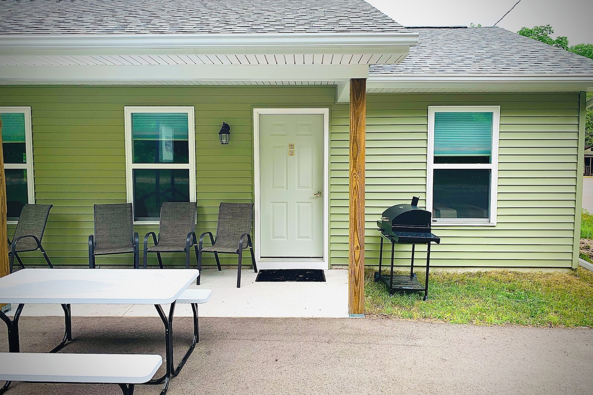A house with a front porch, a grill, and outdoor seating.