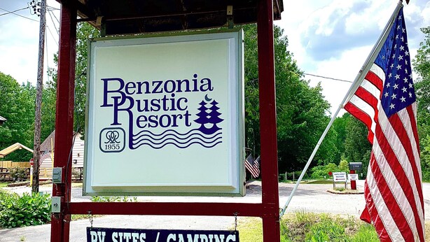 Schild für Benzonia Pestic Resort mit einer amerikanischen Flagge.