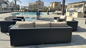 Una zona junto a la piscina con mobiliario de mimbre y una alberca.