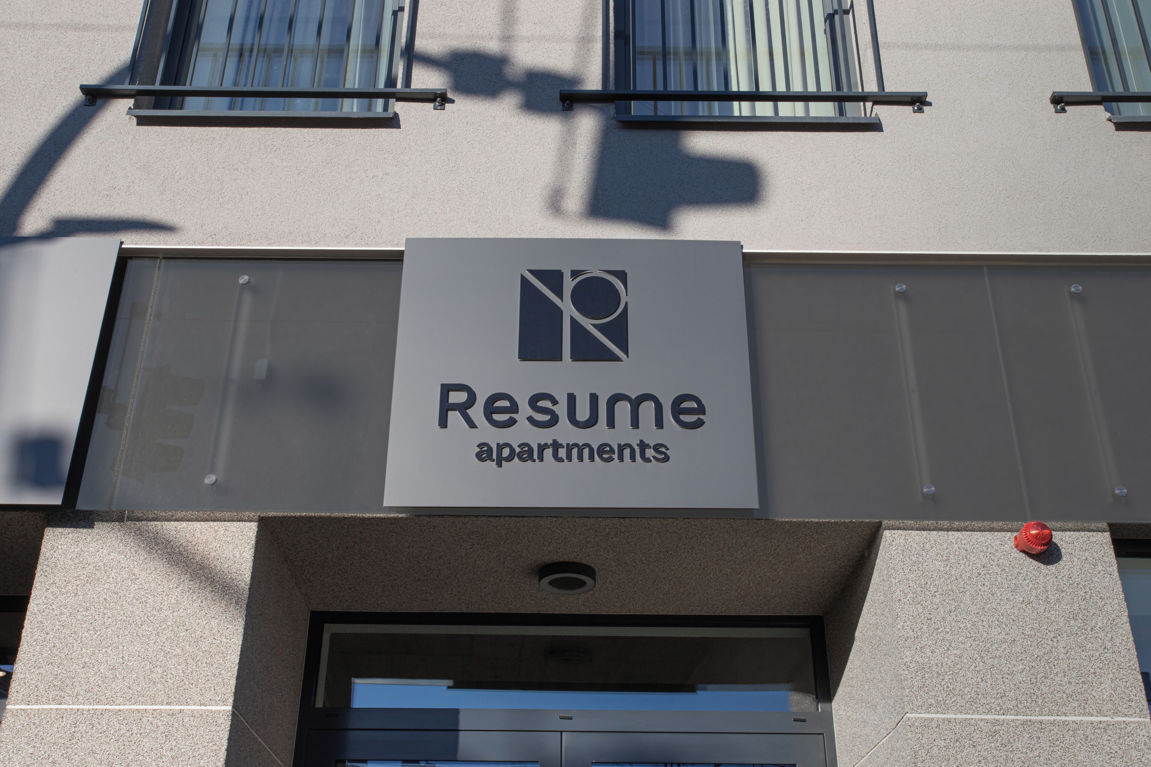 A building with a sign that reads "Resume apartments."