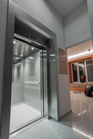 An elevator with a clear floor plan and a sign indicating the lobby direction. - Resume Apartments (Kaunas)