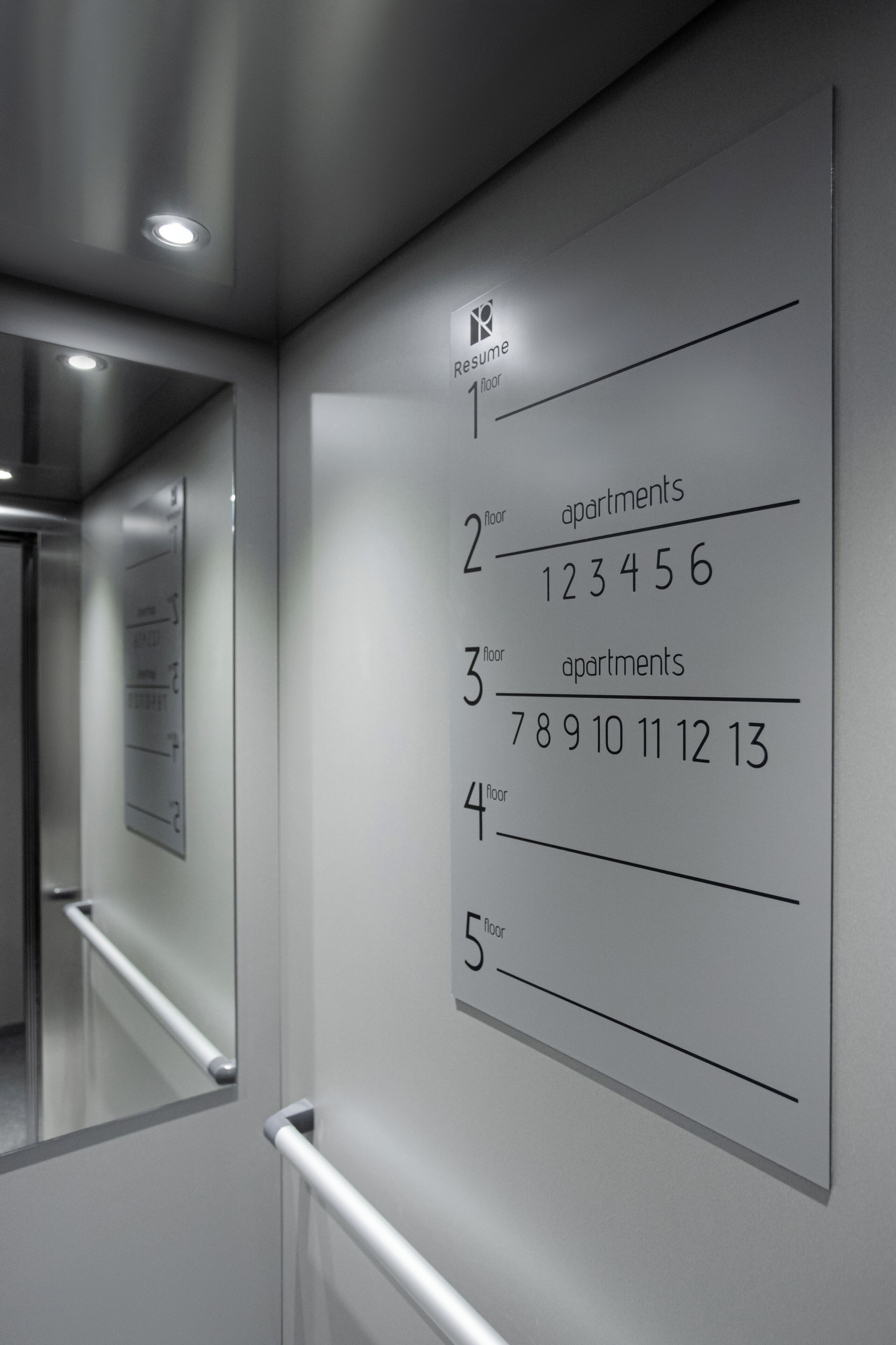A wall with apartment numbers and a handrail.