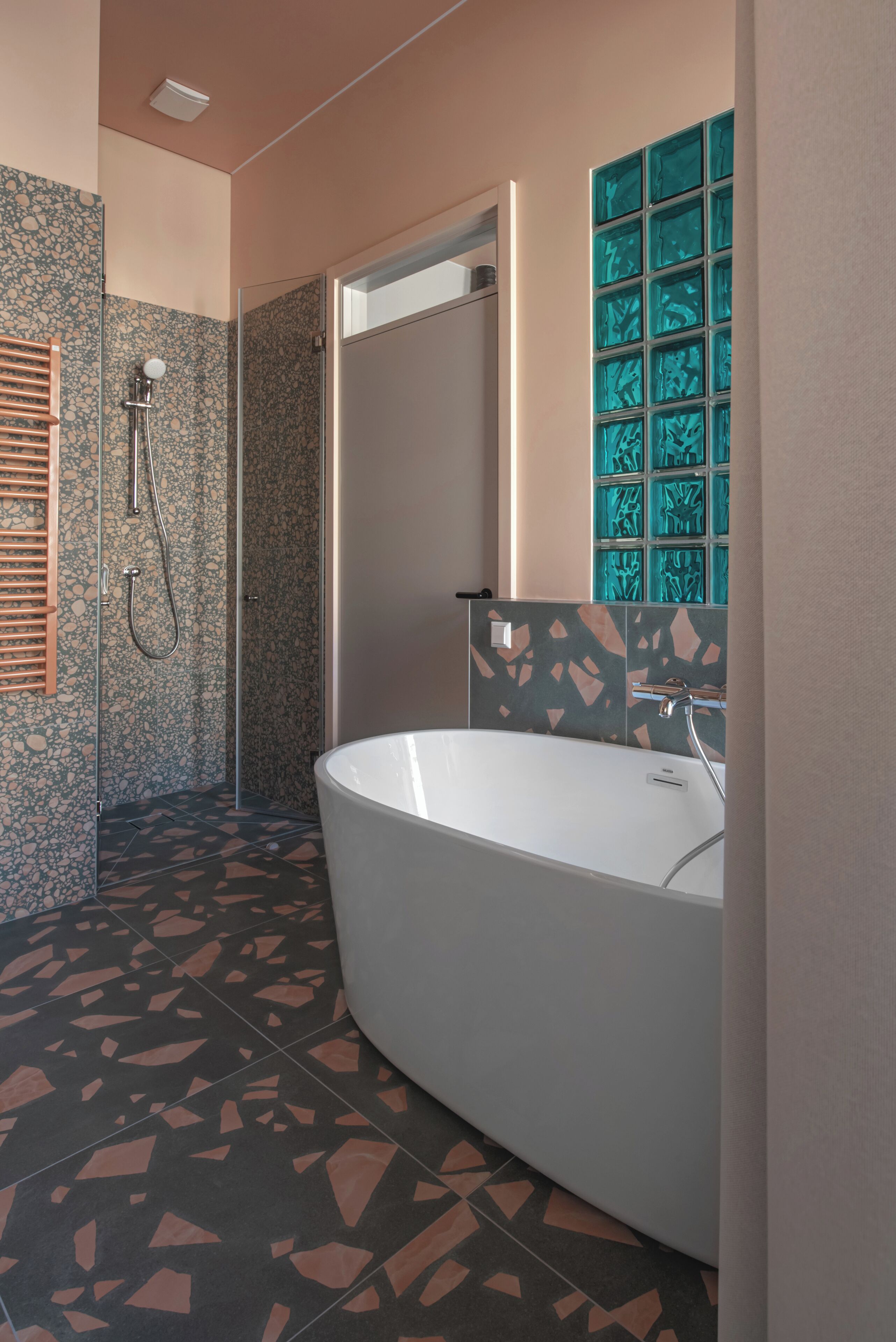 A modern bathroom with a freestanding bathtub, a glass shower enclosure, and a decorative tile backsplash.