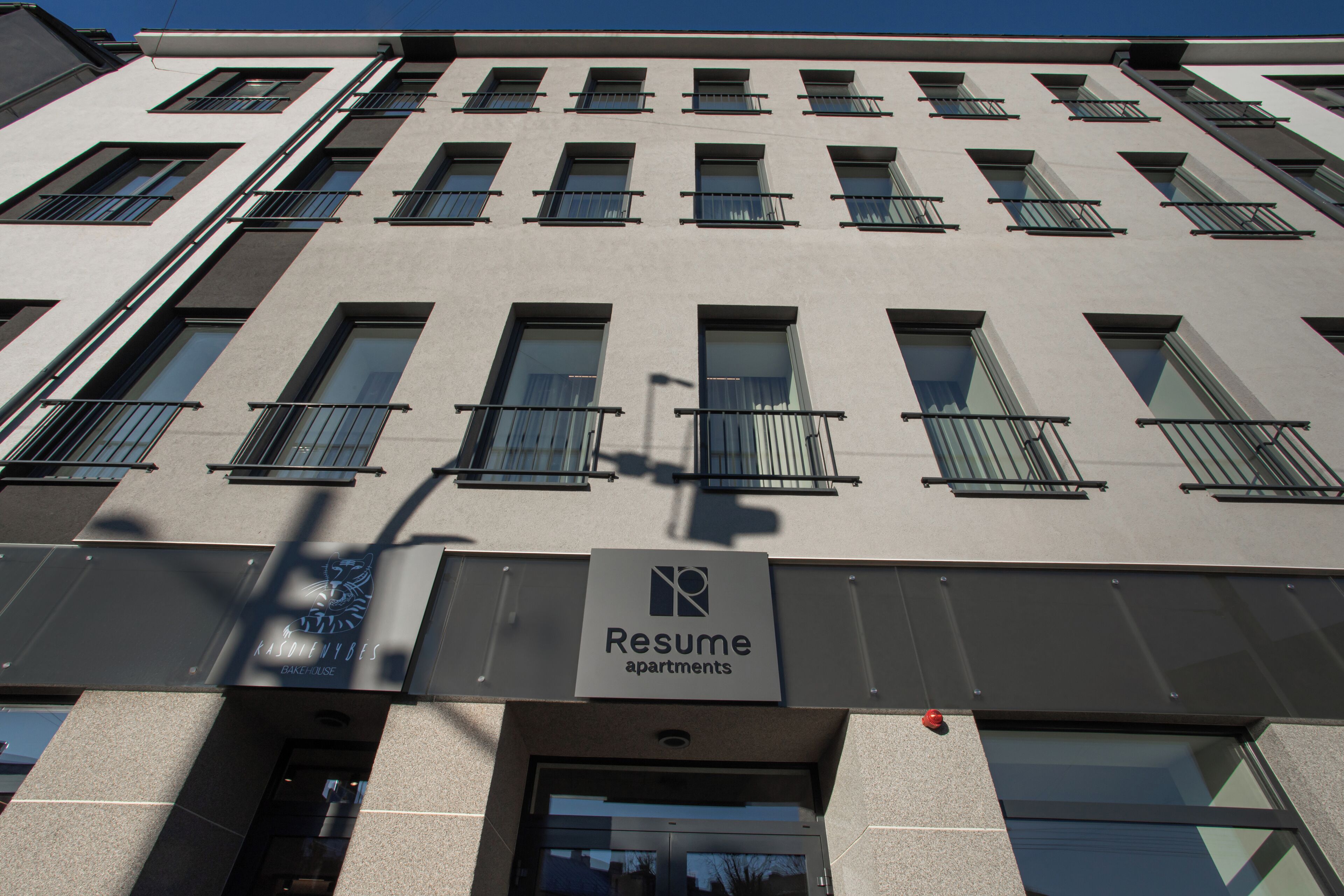 Een gebouw met meerdere ramen en balkons, met de aanduiding 'Resume Apartments'.