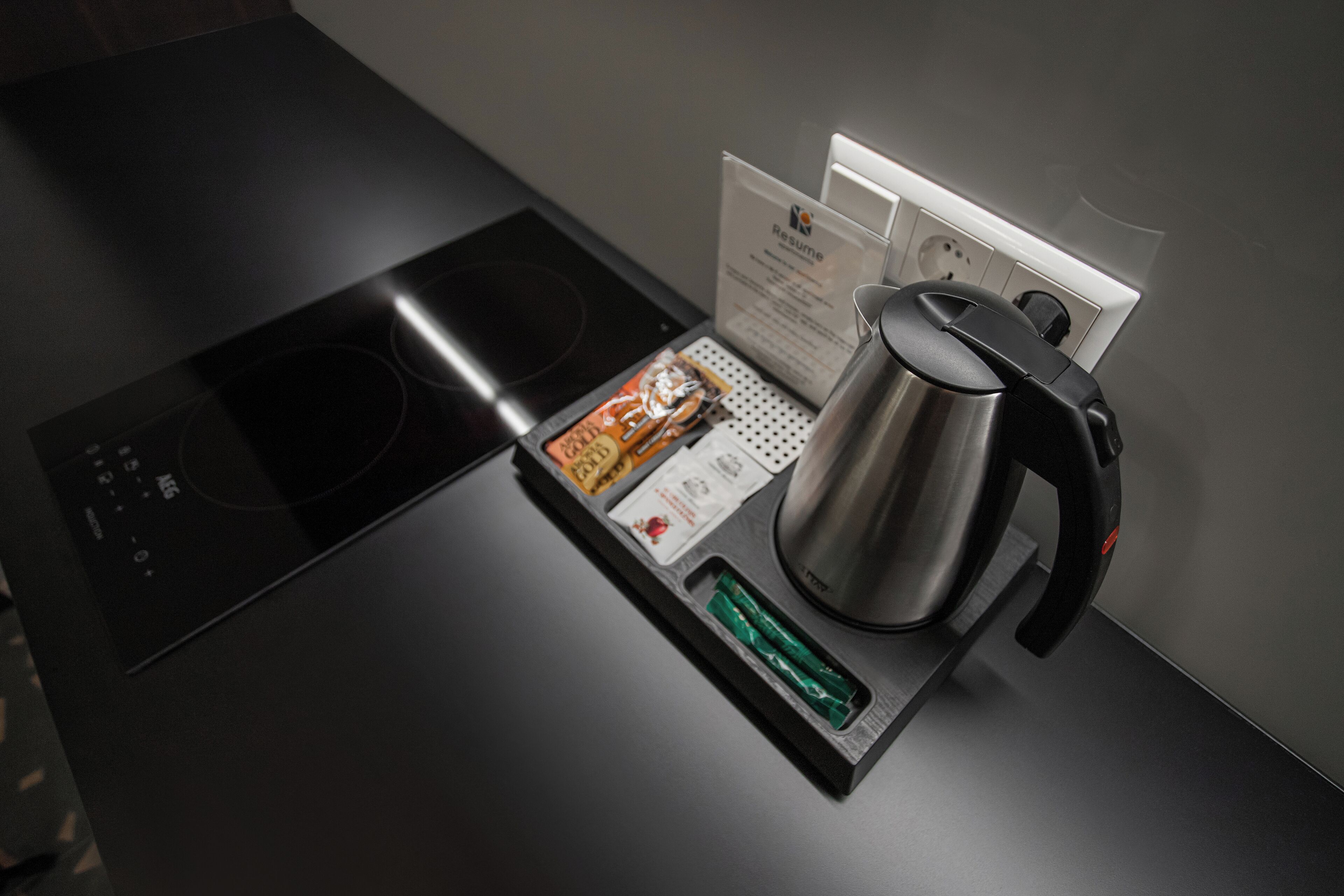 A modern kitchen with a built-in induction cooktop, a stainless steel kettle, and a coffee maker.