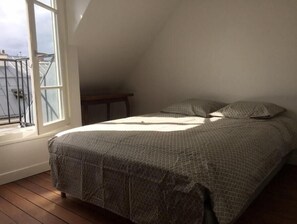 A bedroom with a bed, a window, and a view of the outside. - VUE Tour Eiffel Depuis LE Balcon Studio Lumineux Avec VUE SUR LES Toits DE Paris (Paris)