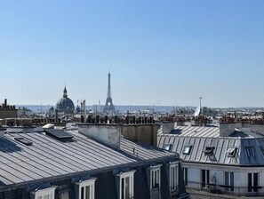 A rooftop view of Paris with the Eiffel Tower and the dome of the Louvre in the background. - VUE Tour Eiffel Depuis LE Balcon Studio Lumineux Avec VUE SUR LES Toits DE Paris (Paris)