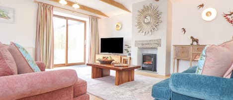 Un salon avec deux canapés, un téléviseur, une cheminée et un plafond en bois.