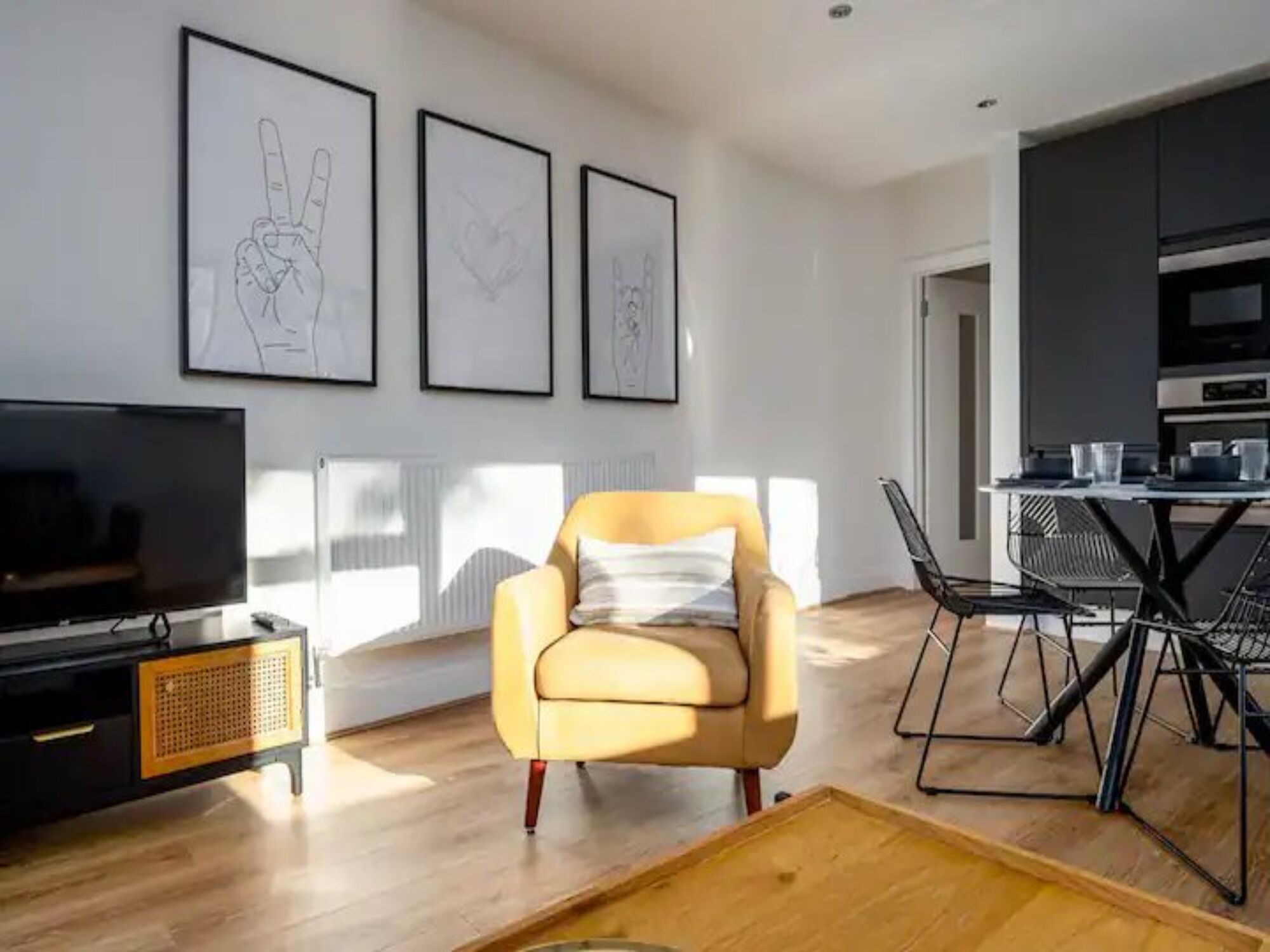 A modern living room with a sofa, a TV, and framed artwork on the wall.