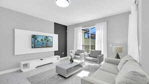 Ein modernes Wohnzimmer mit Flachbildfernseher, einer Couch, einem Couchtisch und einem TV-Schrank.