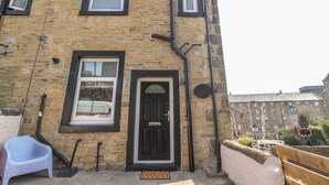 A two-story building with a brick facade, a black door, and multiple windows. - Bridge End (Skipton)