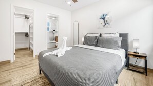 Een moderne slaapkamer met een groot bed, een plafondventilator, een nachtkastje met een lamp en een kledingkast.