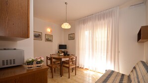 Une pièce chaleureuse avec une table à manger en bois, des chaises, un canapé et un téléviseur.
