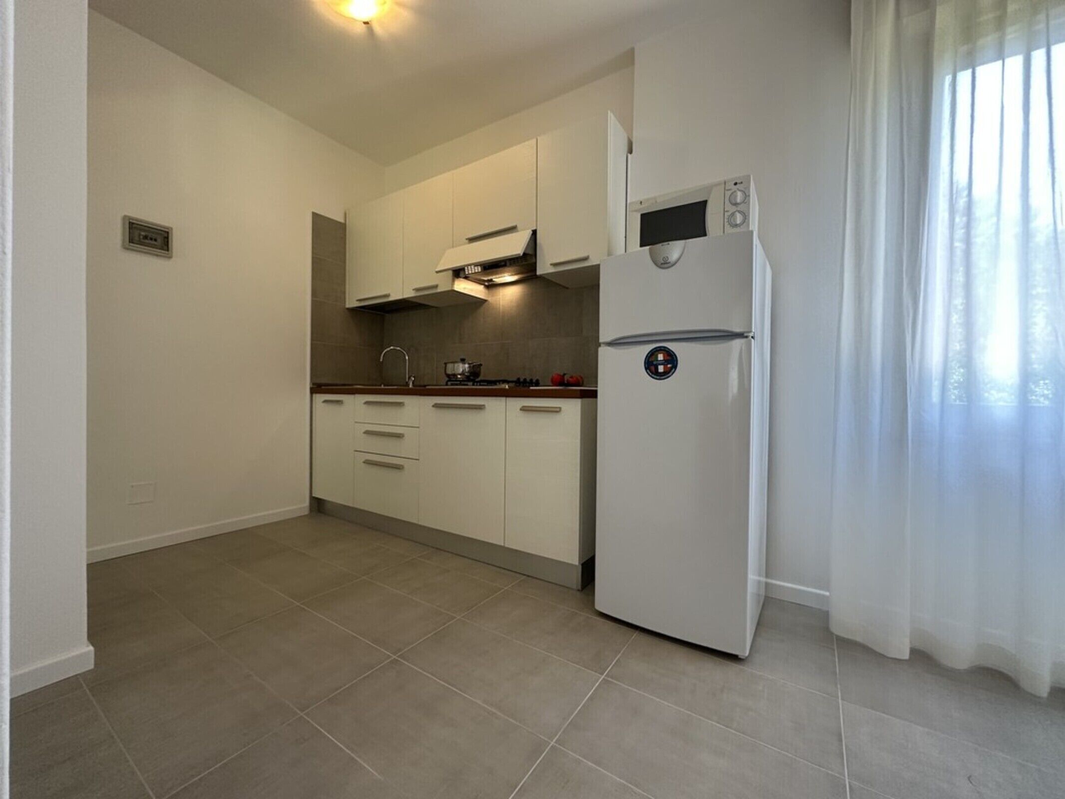 Eine moderne Küche mit weißen Schränken, einem eingebauten Backofen und einem Kühlschrank mit Digitalanzeige.