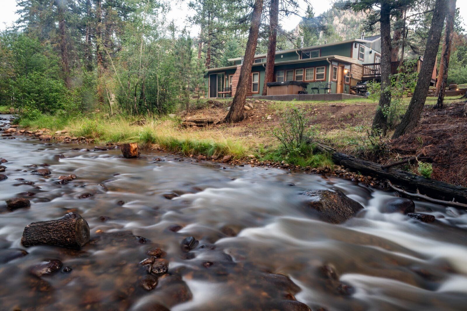 Una casa con vistas a un río y un bosque circundante.