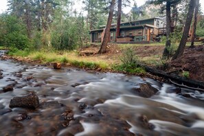 A house with a view of a flowing stream and surrounding forest. - Stonebrook Resort - Adults Only (Estes Park)