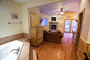 A bathroom with a bathtub, wooden cabinets, and a stone fireplace. - Stonebrook Resort - Adults Only (Estes Park)
