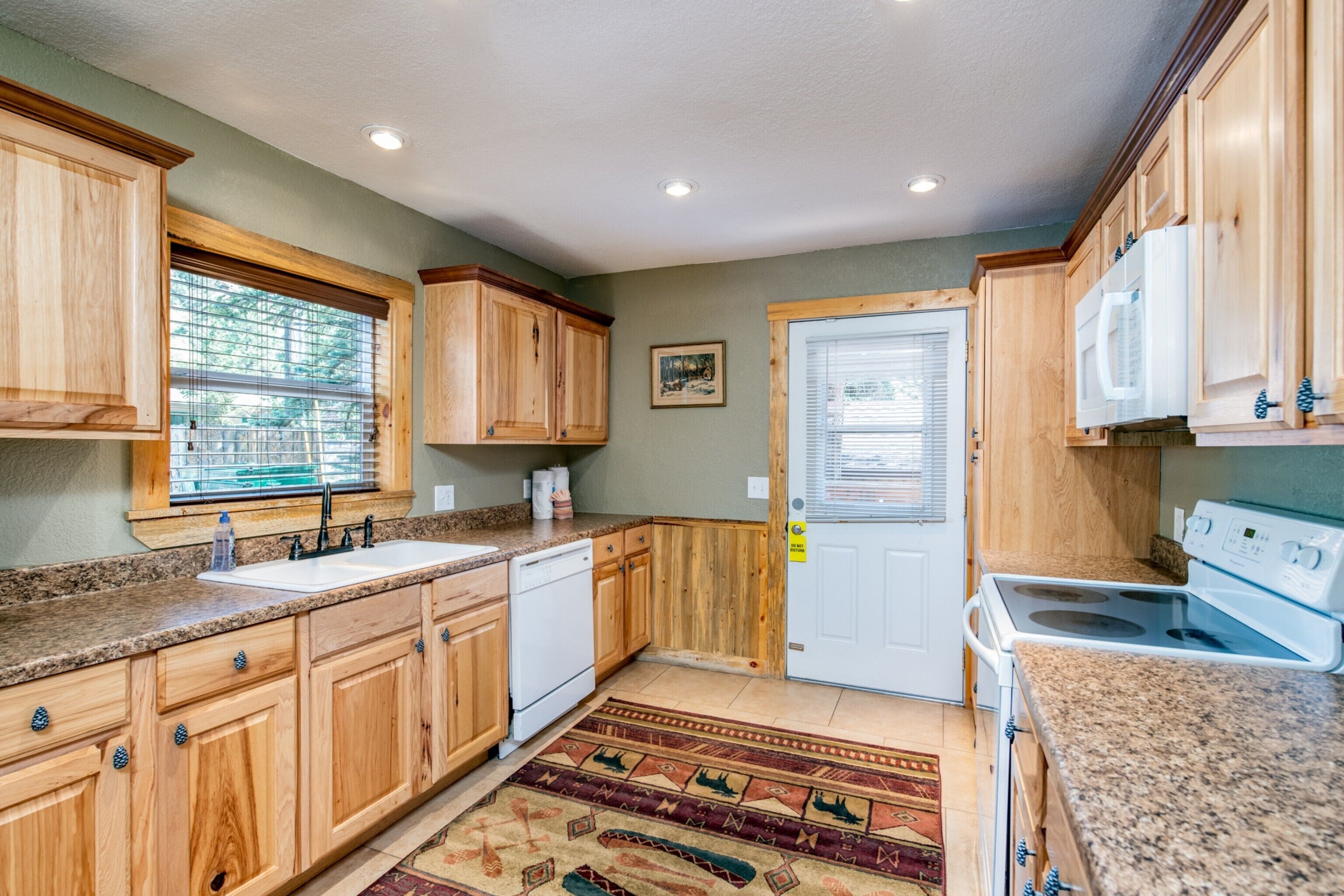 A kitchen with wooden cabinets, a white stove, and a window with blinds.
