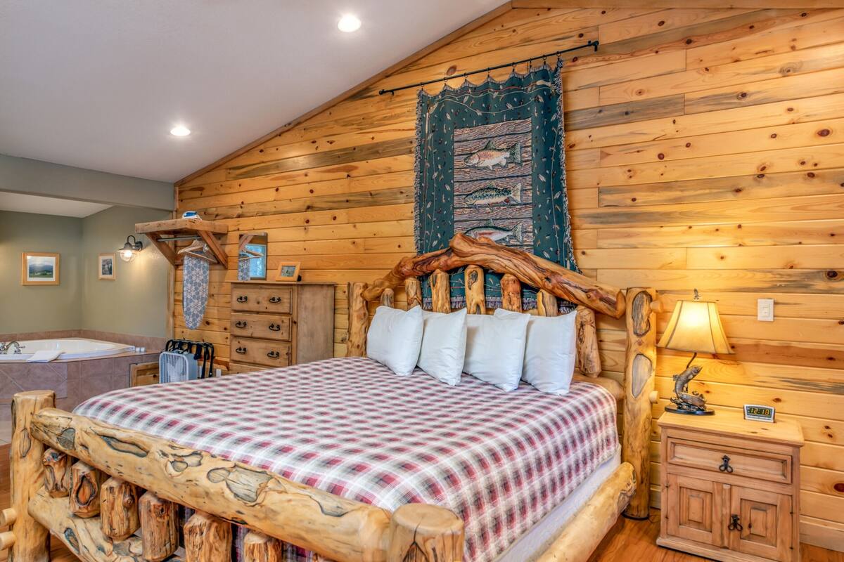 Une chambre à coucher de style cabane en bois, avec un lit, une table de chevet, une lampe et une tapisserie murale.