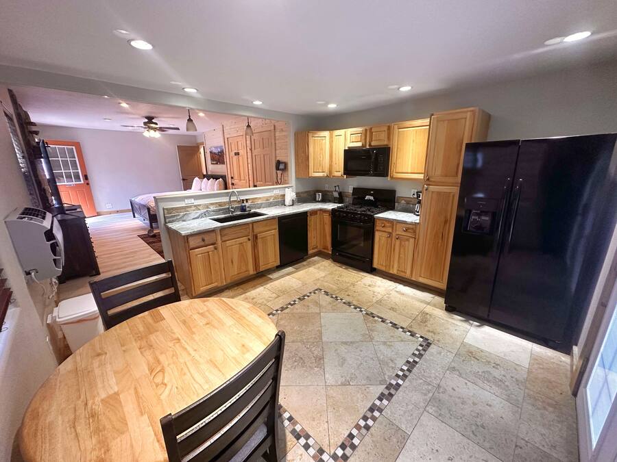 A modern kitchen with wooden cabinets, a black refrigerator, and a central island with a sink.