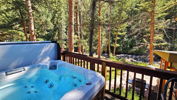 Un jacuzzi en una terraza con vistas a un bosque y un río.