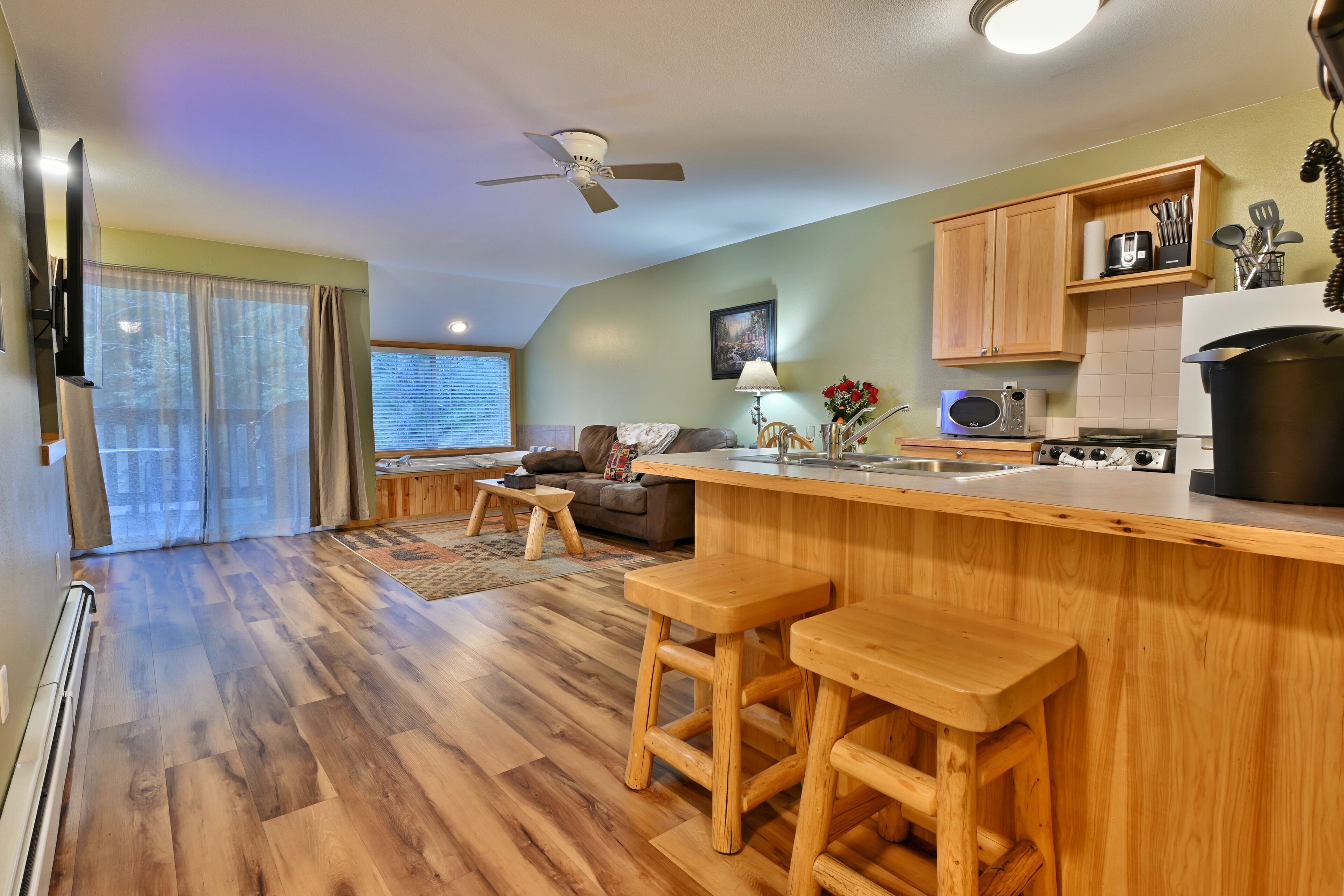 A modern kitchen with wooden countertops, a bar area, and a dining space with wooden stools.