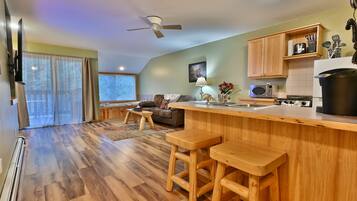 A modern kitchen with wooden countertops, a bar area, and a dining space with wooden stools.