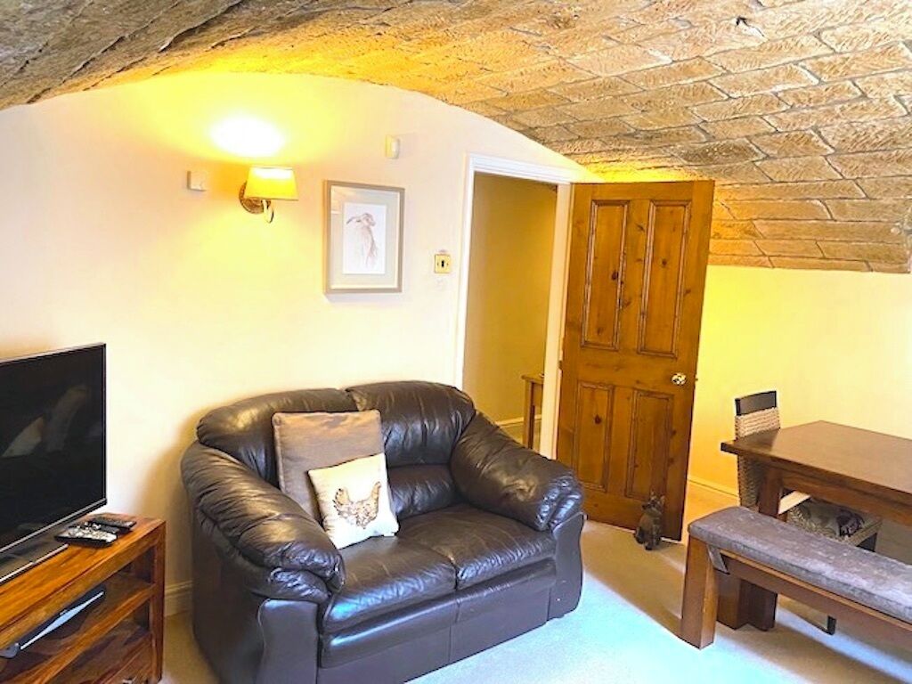 Ein gemütliches Wohnzimmer mit einem Ledersofa, einem Fernseher und einem Holzesstisch.