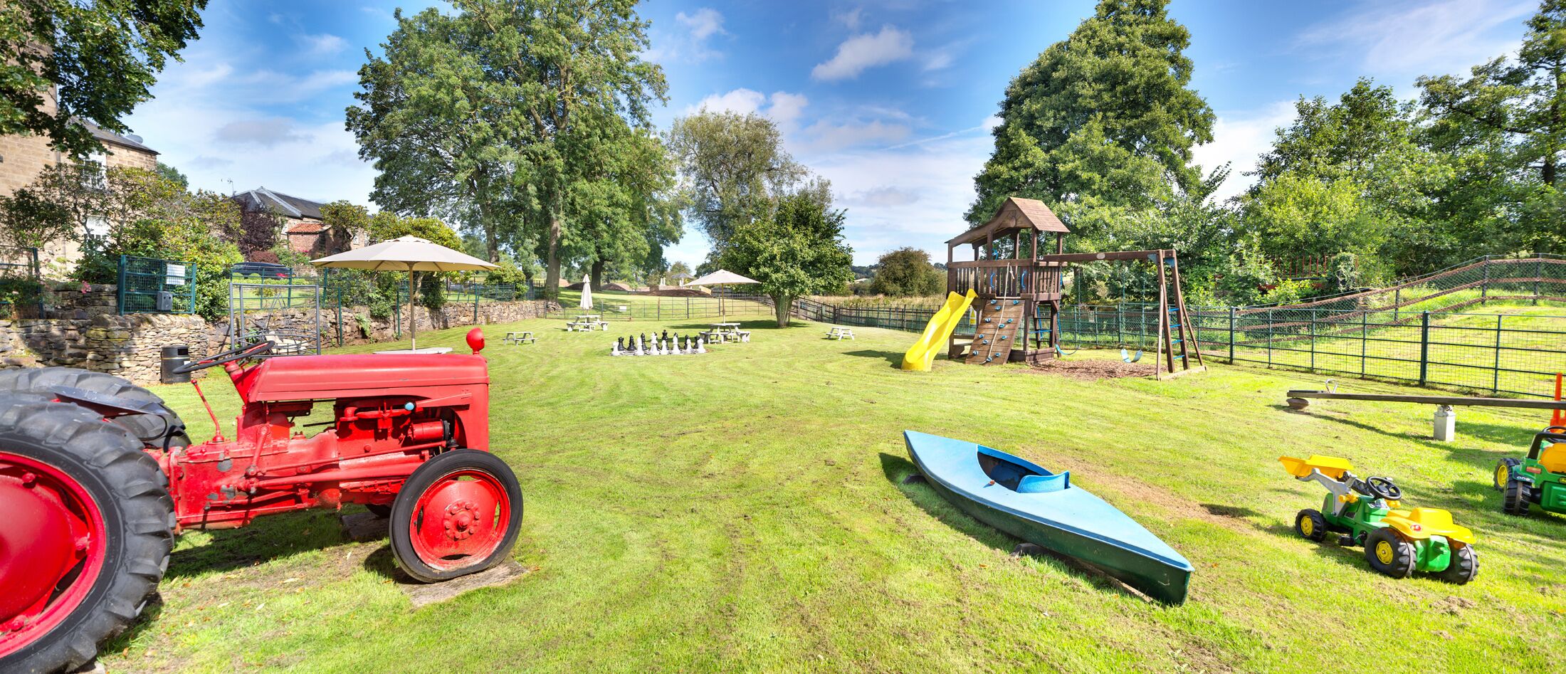 A playground with a slide, swings, and a small boat.