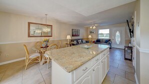 A kitchen with a large island, dining area with chairs, a sofa, and a dining table. - 206 White Sandy-pet Friendly (Panama City Beach)