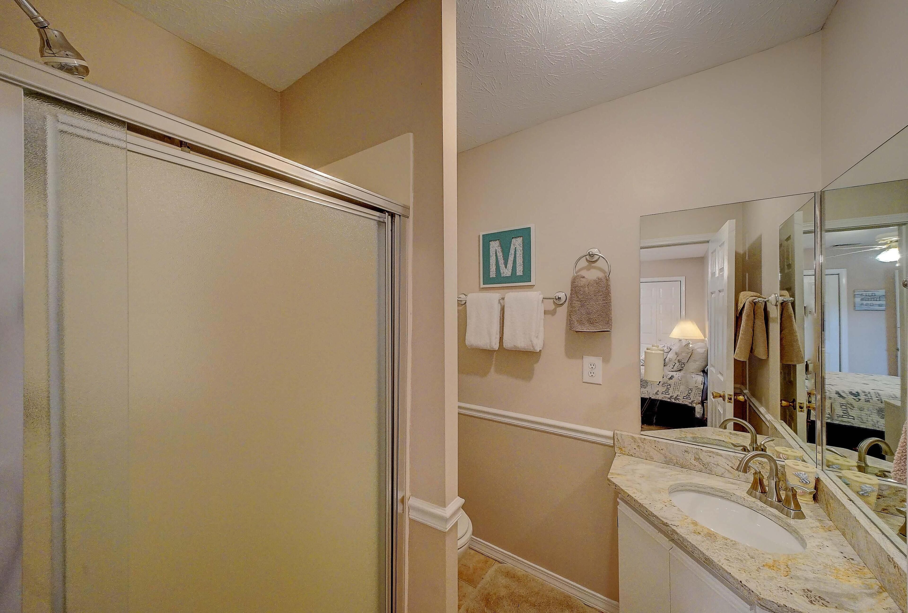 A bathroom with a shower, a sink, and a mirror.