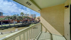 A balcony with a view of a river, palm trees, and buildings in the background. - 206 White Sandy-pet Friendly (Panama City Beach)