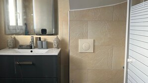 A modern bathroom with a large mirror, a sink with a faucet, and a toilet.