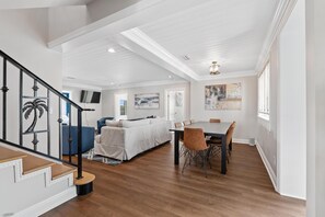 A spacious living area with a dining table, a sofa, and a staircase.
