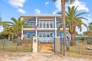 A two-story house with a blue exterior, a balcony, and a flag.