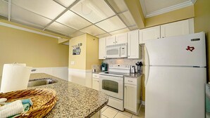 A kitchen with white cabinets, a microwave, stove, and refrigerator. - Edgewater 1008-3 (Panama City Beach)