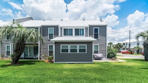 A two-story house with a grey exterior, a small front porch, and a well-maintained lawn. - 7904 Surf Dr #7 (Panama City Beach)