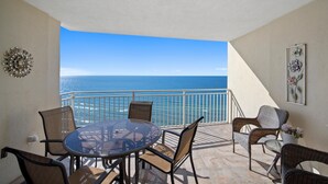 A balcony with a glass table and chairs, overlooking the ocean. - Emerald Beach 2325 (Panama City Beach)