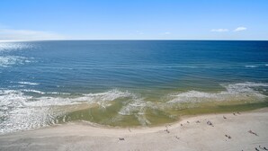 A beach with clear blue water and a sandy shore. - Emerald Beach 2325 (Panama City Beach)