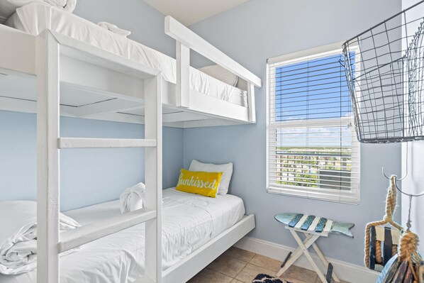 A bunk bed room with a window, a small ironing board, and a hanging rack.
