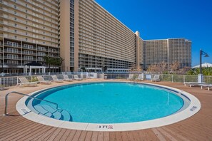 A large outdoor swimming pool surrounded by a wooden deck, with a high-rise building in the background. - Laketown Wharf - 810 (Panama City Beach)
