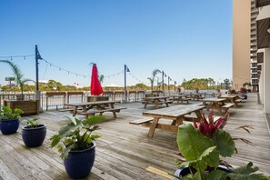 An outdoor patio with wooden picnic tables and potted plants. - Laketown Wharf - 810 (Panama City Beach)