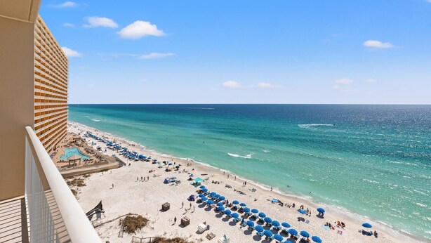 A beach view from a balcony overlooking a sandy beach with umbrellas and a pool area. - Seychelles 1006 (Panama City Beach)