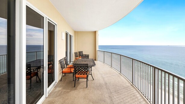 Un balcon avec une table et des chaises, une vue sur l’océan et une balustrade.